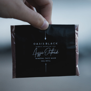 Hand holding a plastic free & home compostable sachet of Oasis Black's Powdered Clay Mud Mask in Aussie Outback - a red dirt coloured facial mask activated with water featuring Australian Clays, Davidson Plum, Lemon Myrtle, Muntrie, Kakadu Plum & Black Seeds. Available exclusively from Oasis Black - makers of All Natural and Organic Botanical Skincare featuring Black Seeds (Nigella Sativa). All products are handmade in small batches to waterless formulations in the Byron Bay hinterland