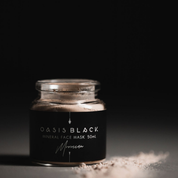 50ml glass jar of Oasis Black's Moroccan Mineral Clay Mud Mask, with some of powder spilled on the bench next to the jar, on a dark background. Moroccan is a brown coloured facial mask activated with water featuring Moroccan Rhassoul Clay, Rosehips, Rose petals & Black Seeds. Available exclusively from Oasis Black - makers of All Natural and Organic Botanical Skincare featuring Black Seeds (Nigella Sativa). All products are handmade in small batches to waterless formulations in the Byron Bay hinterland