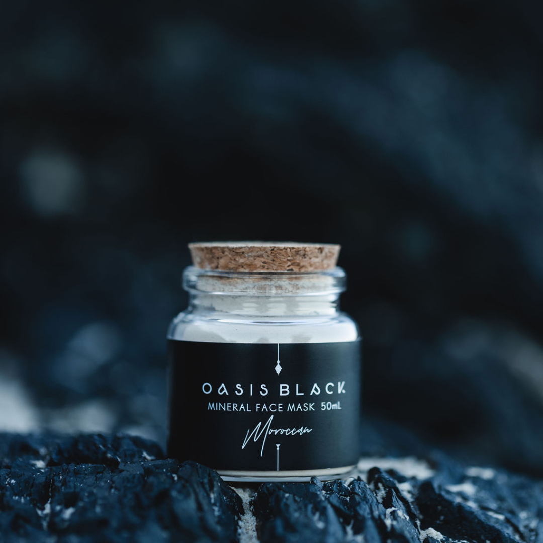 50ml glass jar of Oasis Black's Moroccan Mineral Clay Mud Mask, on a dark rocky background. Moroccan is a brown coloured facial mask activated with water featuring Moroccan Rhassoul Clay, Rosehips, Rose petals & Black Seeds. Available exclusively from Oasis Black - makers of All Natural and Organic Botanical Skincare featuring Black Seeds (Nigella Sativa). All products are handmade in small batches to waterless formulations in the Byron Bay hinterland