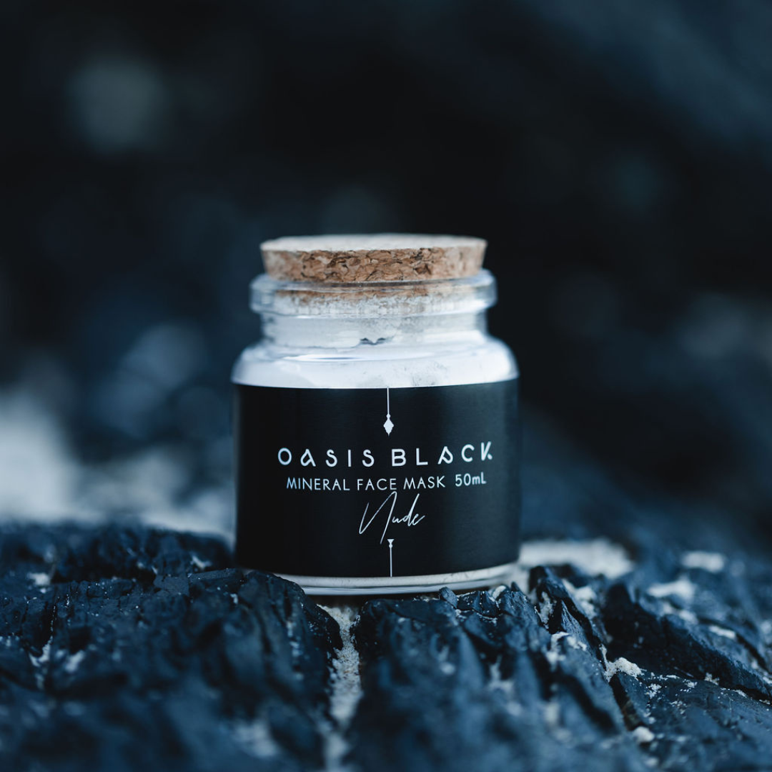 Glass jar (with a cork lid) of Oasis Black Mineral Facial Mask in Nude on a dark rocky background. Nude is a pink coloured mud mask activated with water featuring French Pink Clay, Australian Clays, Aloe Vera, Chamomile, Rose petals and Black Seeds. Available exclusively from Oasis Black - makers of All Natural and Organic Botanical Skincare featuring Black Seeds (Nigella Sativa). All products are handmade in small batches to waterless formulations in the Byron Bay hinterland