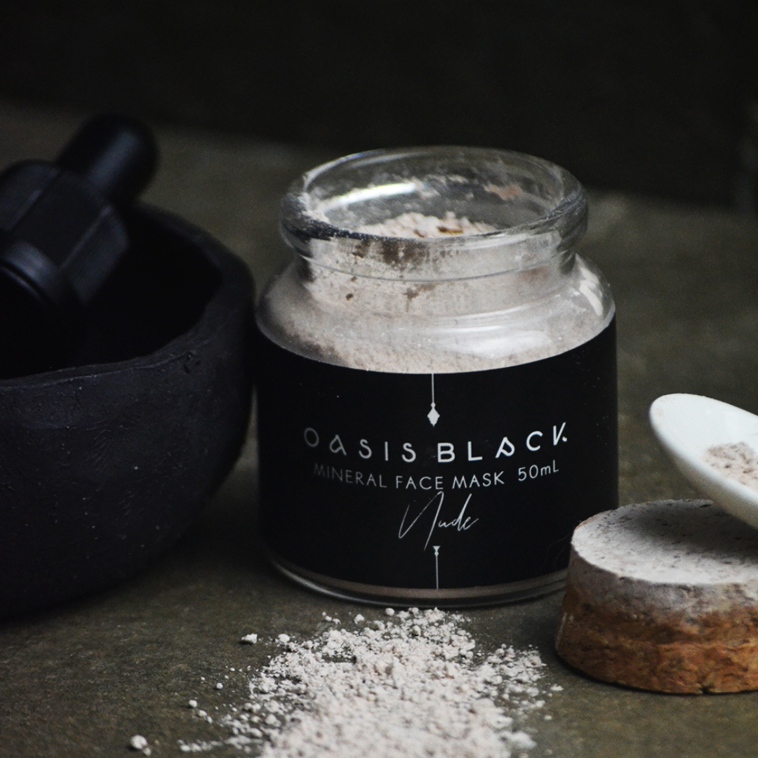 Glass jar of Oasis Black's Nude Mineral Clay Mud Mask with the pink clay powder spilled out on a grey surface. Nude is a pink coloured facial mask activated with water featuring French Pink Clay, Australian Clays, Aloe Vera, Chamomile, Rose petals and Black Seeds. Available exclusively from Oasis Black - makers of All Natural and Organic Botanical Skincare featuring Black Seeds (Nigella Sativa). All products are handmade in small batches to waterless formulations in the Byron Bay hinterland