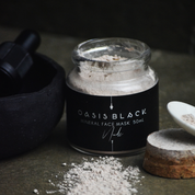 Glass jar of Oasis Black's Nude Mineral Clay Mud Mask with the pink clay powder spilled out on a grey surface. Nude is a pink coloured facial mask activated with water featuring French Pink Clay, Australian Clays, Aloe Vera, Chamomile, Rose petals and Black Seeds. Available exclusively from Oasis Black - makers of All Natural and Organic Botanical Skincare featuring Black Seeds (Nigella Sativa). All products are handmade in small batches to waterless formulations in the Byron Bay hinterland