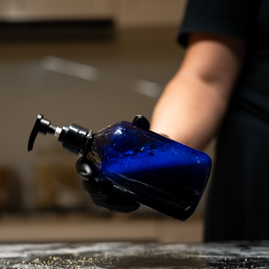 Person shaking a blue bottle containing Oasis Black's Face & Body, Powder to Liquid Cleanser Concentrate in HEMP and water. Oasis Black's Cleanser Concentrates are All natural, zero waste castile soap based powdered cleansers that turn into liquid face and body wash with water. Available exclusively from Oasis Black - makers of All Natural and Organic Botanical Skincare featuring Black Seeds (Nigella Sativa). Handmade in small batches to waterless formulations in the Byron Bay Hinterland.